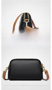 Detail of dual gold zippers and litchi grain black leather on shell-shaped bag