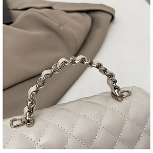 Detail of woven chain strap and quilted leather on beige crossbody bag