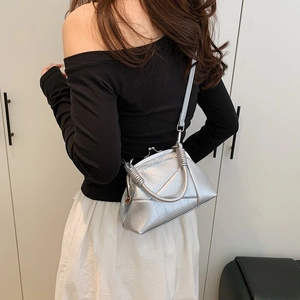Detail of silver crocodile-embossed frame bag with lace trim and wrapped handle