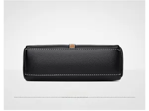 Detailed bottom view of black pebble leather shell bag with white stitching and brown trim