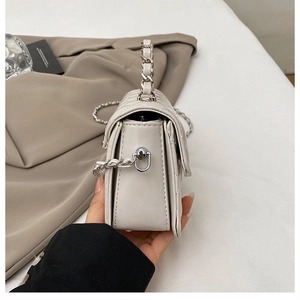 Detail view of the quilted cream crossbody bag showing silver chain and accordion side