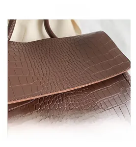 Close-up of brown crocodile embossed leather texture on a high-quality shoulder bag