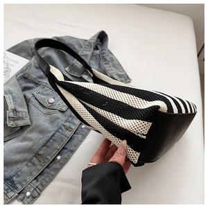 Close-up of woven tote bag with black and white stripes and leather shoulder strap