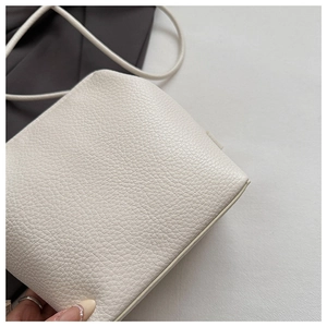 Close-up of premium white litchi pattern leather texture on a minimalist crossbody bag