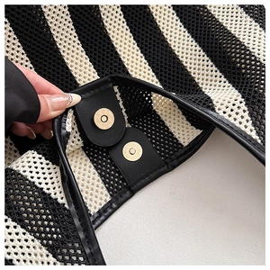 Detail of nautical striped tote bag showing magnetic gold buckle and mesh fabric texture
