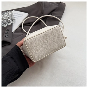 Detail showing the rectangular base and neat stitching of the cream leather crossbody bag