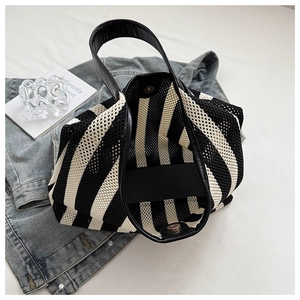 Macro detail of nautical striped mesh tote bag featuring black PU handle and metal magnetic snap