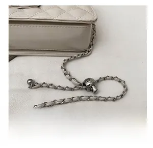 Detail of beige quilted leather chain strap and adjustable metallic ball buckle