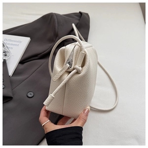 Close-up of off-white lychee pattern leather texture and knotted strap on luxury handbag