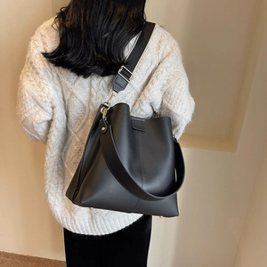 Large black bucket bag with striped wide strap and matte leather shown on a model