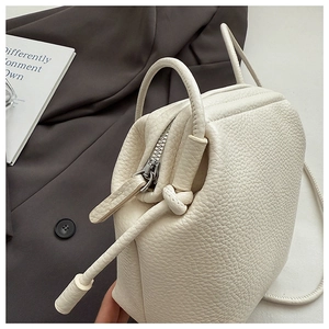 Detailed close-up of cream-white litchi grain leather texture and silver metal zipper