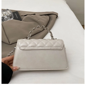 Detail of quilted leather crossbody bag with silver metal chain handle and luxury texture