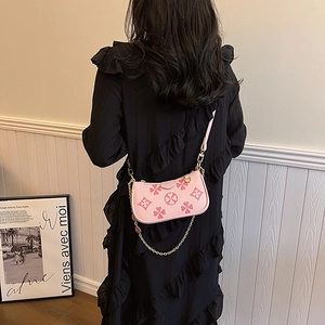 Pink embossed clover baguette bag with gold chain strap shown on a model