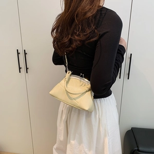 Detail of cream kiss-lock handbag featuring a unique knotted handle and smooth texture
