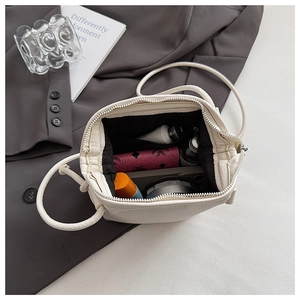 Top view of white pebble leather crossbody bag interior showing phone and makeup storage