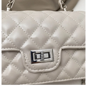 Macro shot of beige quilted leather texture and silver metallic twist lock closure