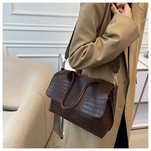 Détail d'un sac à bandoulière en cuir marron foncé effet crocodile et boucles dorées