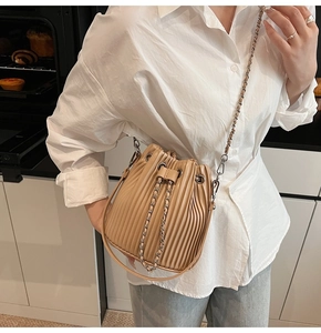 Detail of pleated khaki leather bucket bag with metallic drawstring and silver chain strap