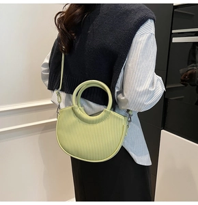 Detail of pistachio green pleated crescent bag showing texture and round handle