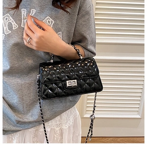 Detail of black quilted patent leather handbag with silver twist lock and chain strap