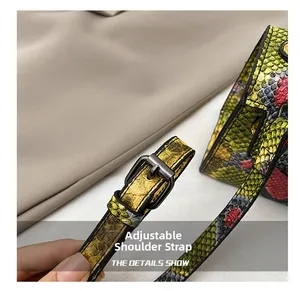 Detail of adjustable shoulder strap with metal buckle on snakeskin print handbag