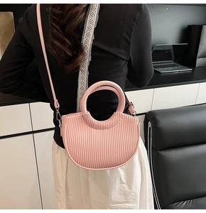 Detail of pink pleated crescent bag showing leather texture and fixed round handle