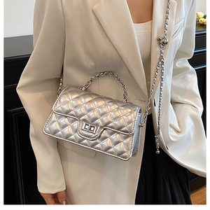Detail of silver metallic quilted crossbody bag with metal chain and top handle strap