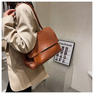 Détail du sac à main marron foncé à motif crocodile sur un modèle en blazer beige