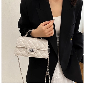 Detail of beige quilted chain bag with silver twist lock and polished metallic handle