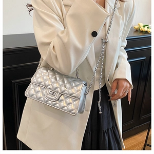 Detail of silver quilted crossbody bag with metallic chain strap and turn-lock closure