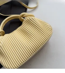 Detailed view of yellow pleated PU handbag with elegant knotted handle and soft texture