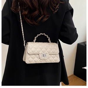 Detail of white quilted crossbody bag with silver chain strap and metallic twist lock