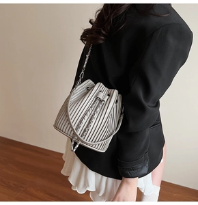 Detail of light grey pleated bucket bag with metal chain strap and drawstring closure