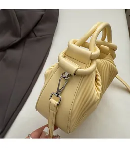 Detail view of premium silver hardware and pleated leather texture on yellow handbag