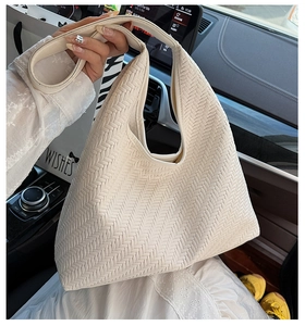 Detail of off-white woven tote bag with V-shaped texture on a car interior background