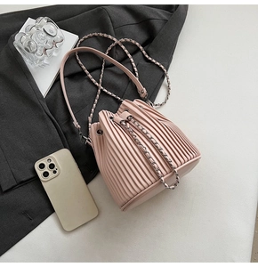 Pink pleated bucket bag with silver metal chain strap shown in a modern lifestyle setting