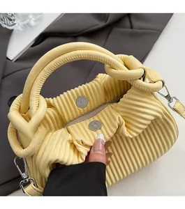 Macro detail of yellow pleated bag featuring a magnetic snap closure and metal hooks
