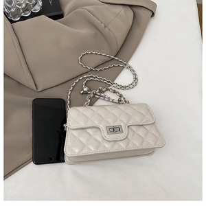Detail of quilted cream crossbody bag with silver twist lock and chain strap