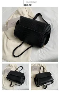 Détail du sac à main noir à motif crocodile avec garniture dorée et sangle tissée