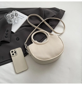 Detail of off-white pleated PU leather crossbody bag with round handle and adjustable strap