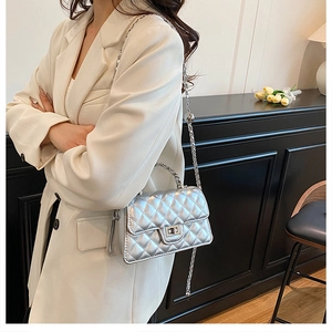 Detailed view of silver quilted crossbody bag with metal chain strap and twist lock