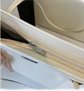 Detail shot of a white woven tote bag featuring a high-gloss finish and smooth silver zipper