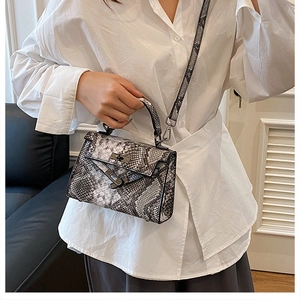 Fashionable snake print top handle bag styled with white shirt in a modern interior