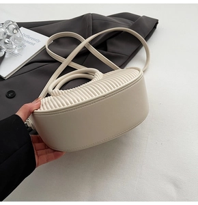 Detail of cream white leather handbag featuring elegant gathered pleats and a top handle