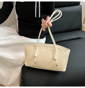 Detail der beigen Falten-Tote-Bag mit goldenen Metallspitzen und Knotenelementen