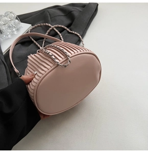 Detail of light pink pleated bucket bag featuring vertical texture and silver chain strap