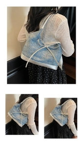 Close-up of denim tote bag with silver bow detail and metallic leather trim accents