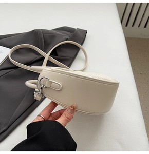 Detailed side view of cream half-moon bag featuring sleek silver hardware D-ring