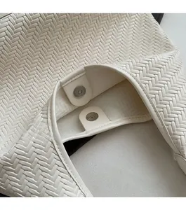 Close-up of cream woven bucket bag showing intricate basket-weave texture and magnetic closure