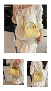 Close-up of a pale yellow pleated satchel with accordion folds and cylindrical handle
